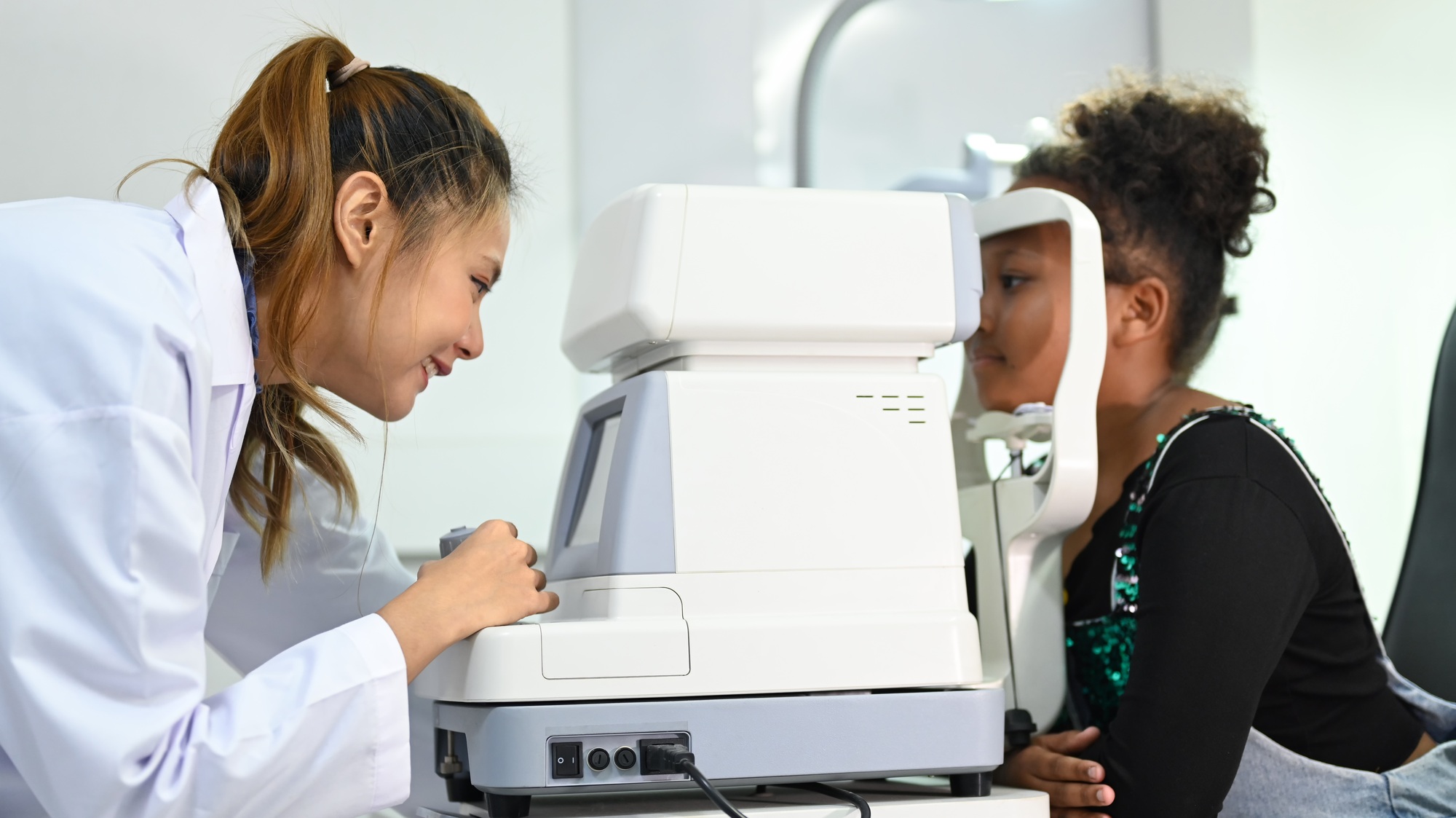 Image of little girl checking eyesight on auto refractor in ophthalmologist clinic.